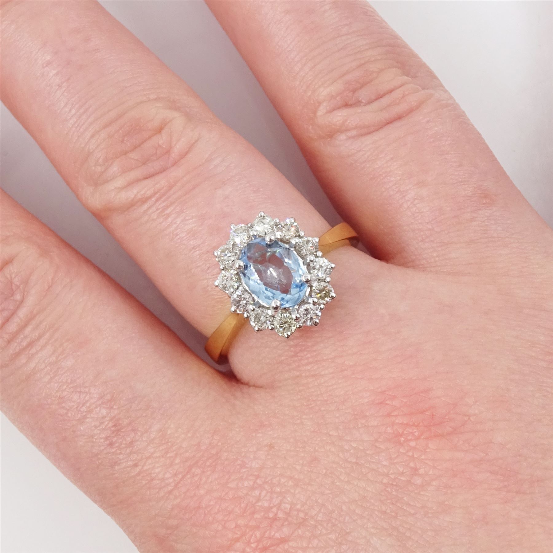 18ct gold aquamarine and diamond cluster ring, oval cut aquamarine of approx 0.80 carat, with round brilliant cut diamond surround, London 2022, total diamond weight approx 0.55 carat