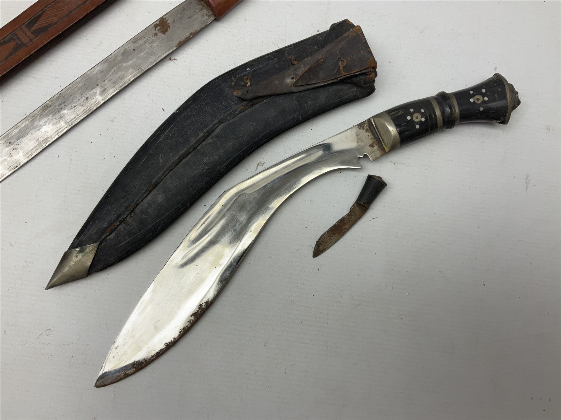 Indian kukri with 29cm curving steel blade and nickel mounted horn grip; in leather covered scabbard with one skinning knife L42cm overall; Hitler Youth knife with scabbard in relic condition; and three African graduated knives each with crudely carved wooden grips and painted leather covered scabbards (5)