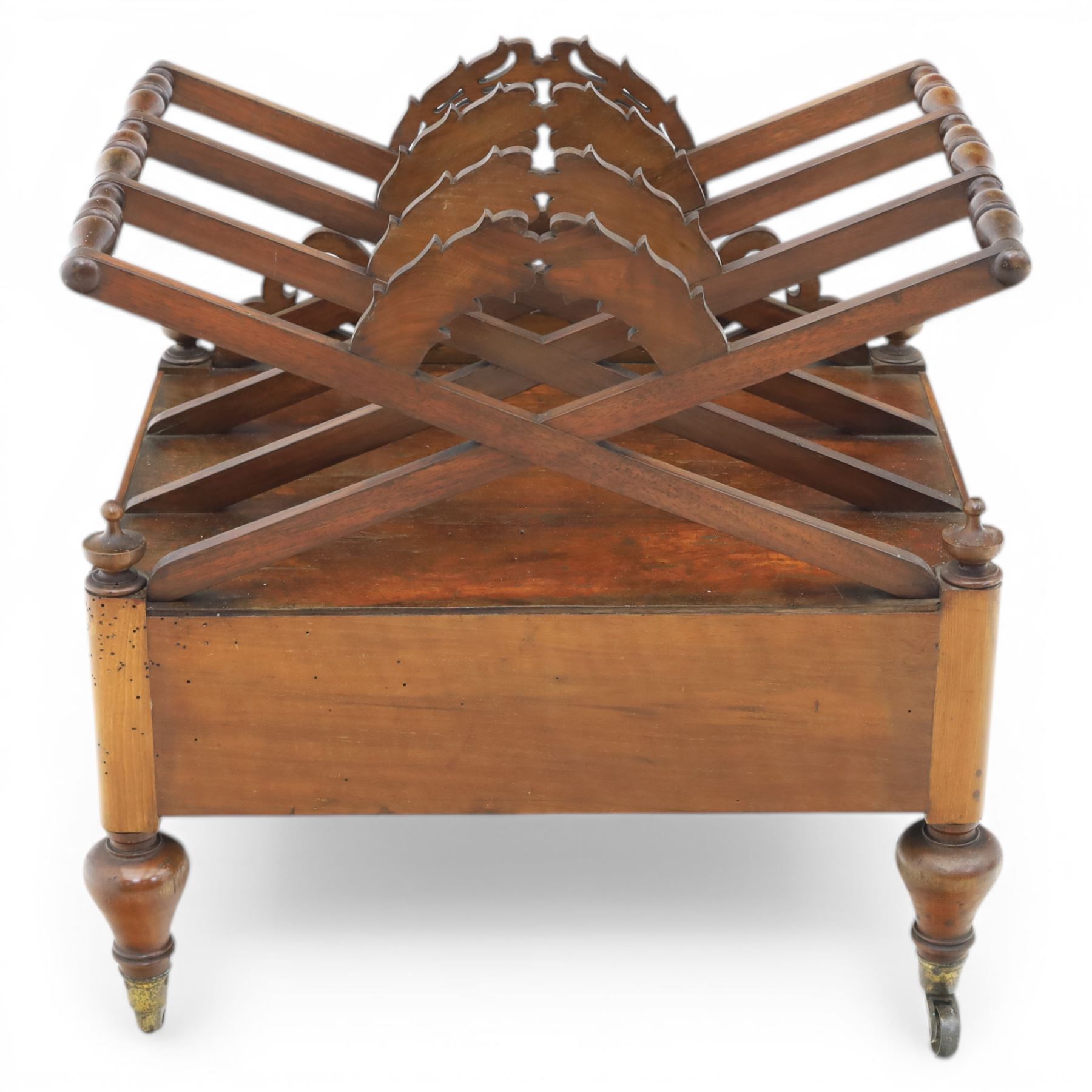 19th century mahogany music canterbury, with pierced dividers united by turned handles, above a single frieze drawer, raised upon baluster supports on brass castors