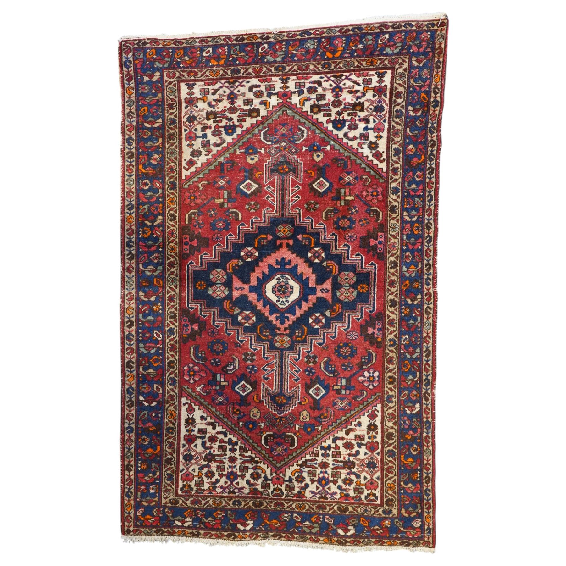 Persian Heriz crimson ground carpet, the central navy geometric medallion on a red crimson ground field, surrounded by further geometric stylised motifs and foliate designs, enclosed by multiple guard-lines  