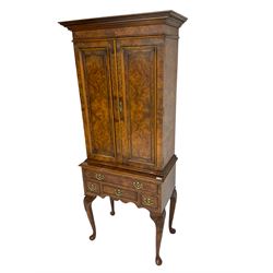 Queen Anne style figured walnut drinks cabinet on stand, two doors enclosing mirrored interior with shelves and slide, the stand fitted with four drawers on shell carved cabriole legs