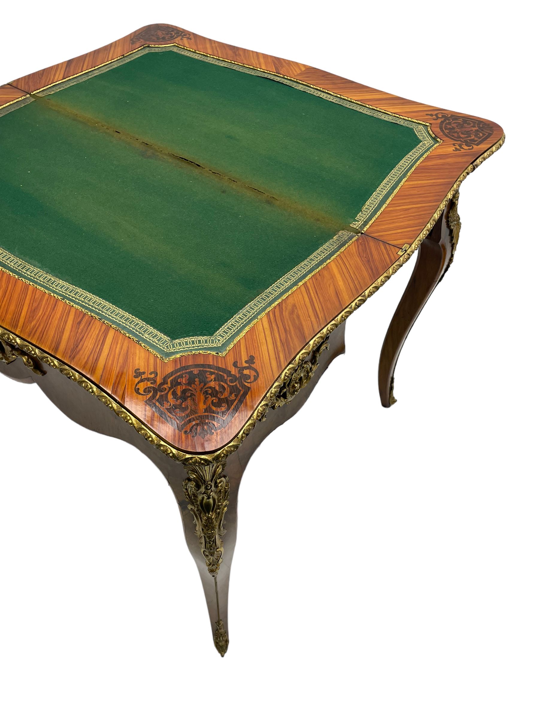 20th century French walnut and Kingwood card table, shaped fold-over top with figured quarter-matched veneers and floral egg and dart moulded edge in gilt metal, shaped aprons decorated with shell motifs with extending foliage, pull-out action base revealing storage well, on cabriole supports with ornate gilt metal mounts 
