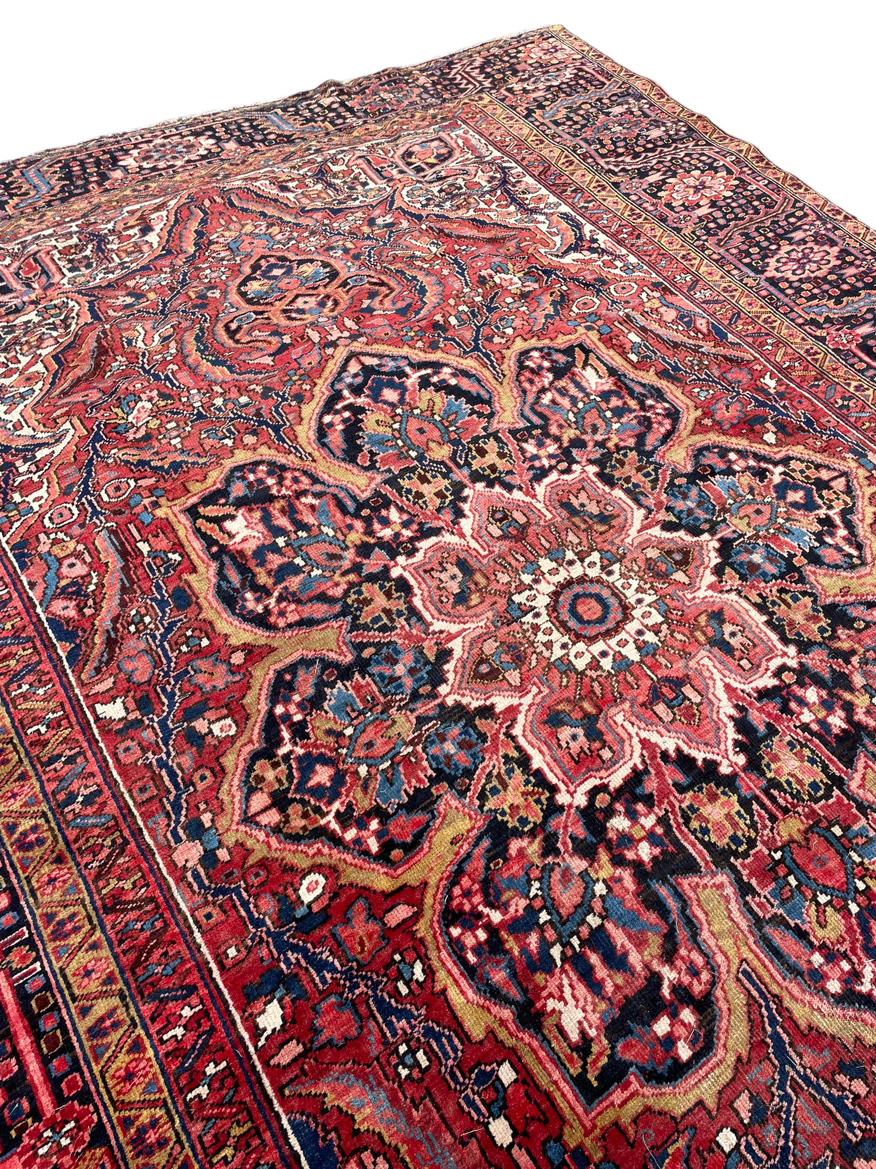 Antique Persian coral ground carpet, the large central floral pole medallion with extending foliate designs, the thick guarded indigo border with repeating flower heads and circles