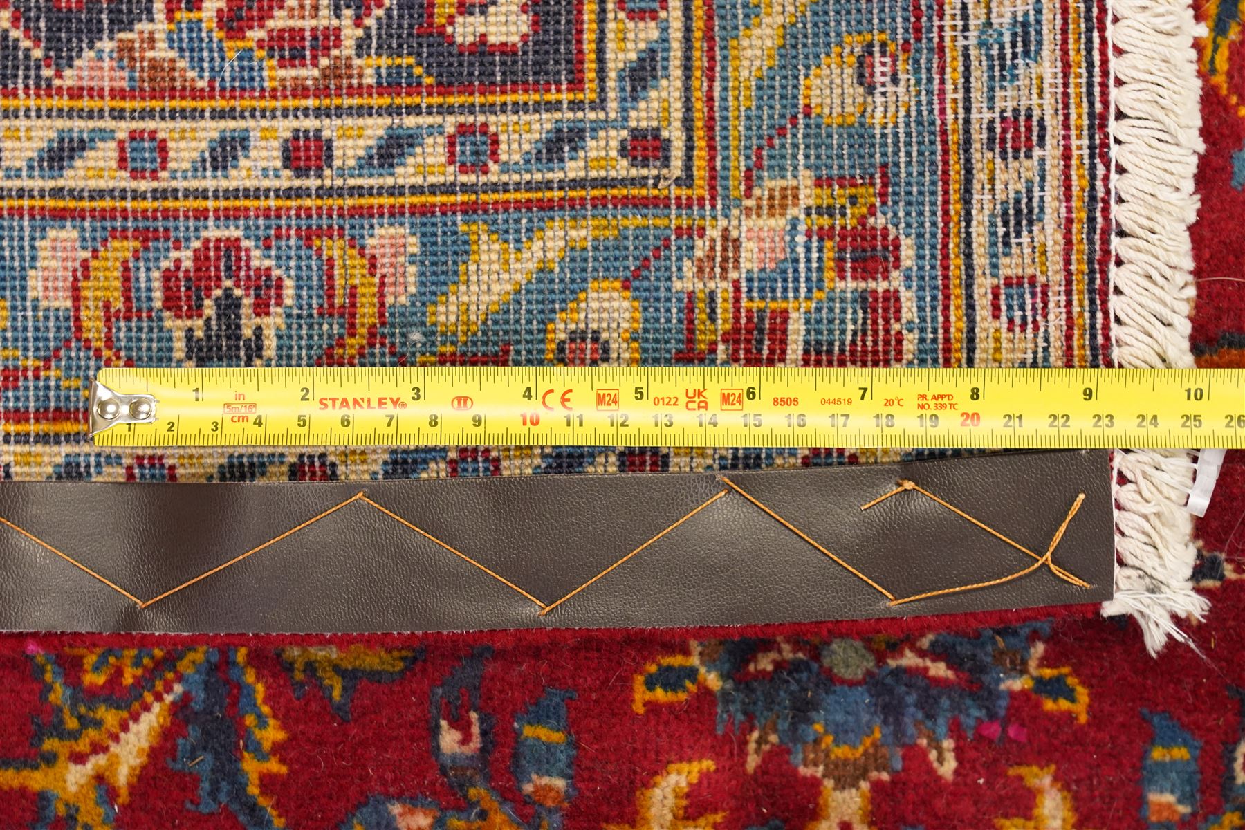 Persian Kashan hand-knotted carpet, madder red ground centred by shaped dark navy, ivory and pale blue floral medallion with pendants, surrounded by scrolling vines, palmettes and flowerheads, dark navy spandrels, enclosed by dark navy floral border with multiple floral guard stripes