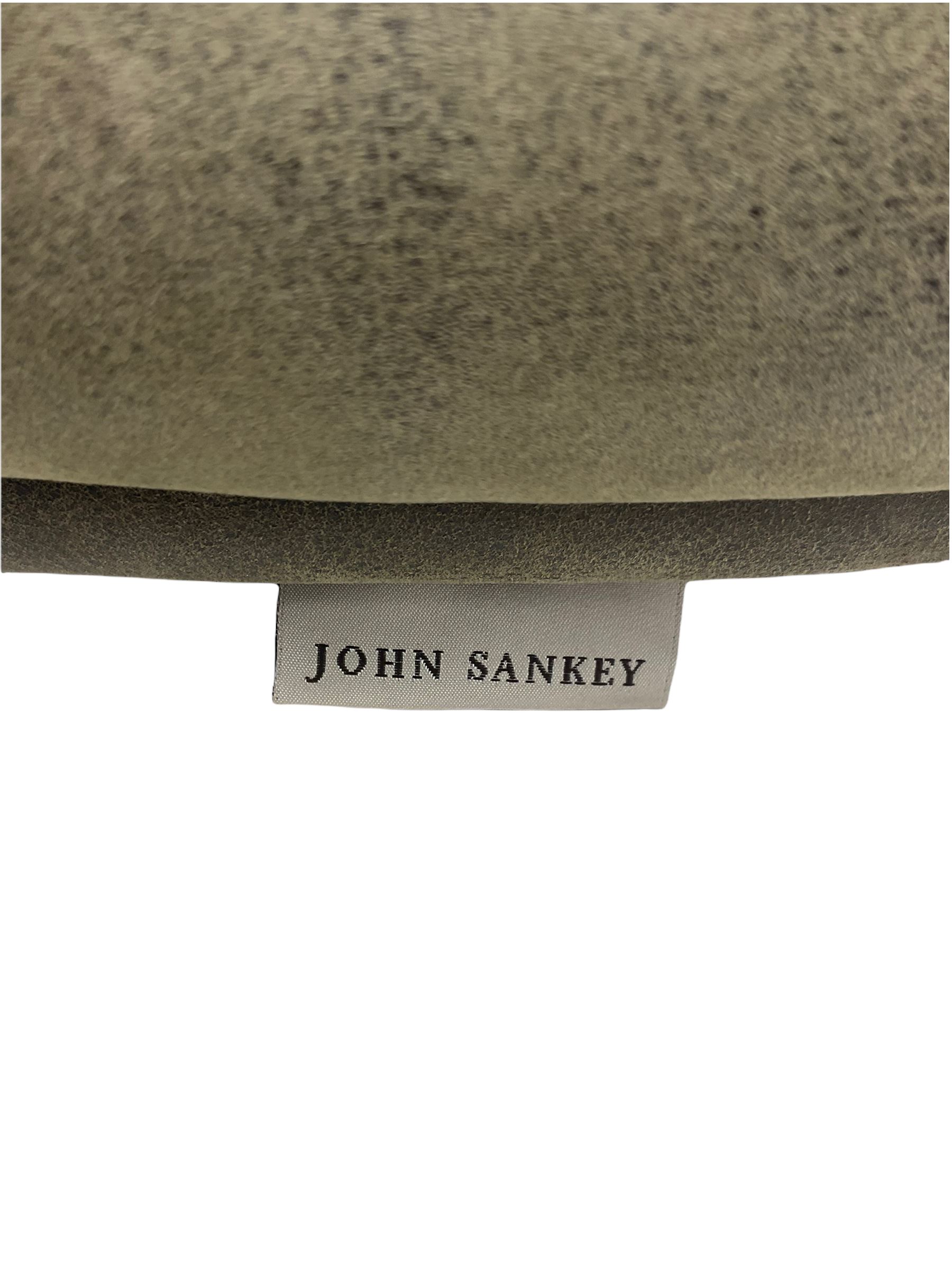 John Sankey - low armchair, buttoned back upholstered in tartan patterned fabric with contrasting grey leather, raised on turned and ebonised front feet with brass and ceramic castors, with matching foot stool