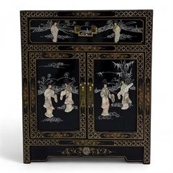 20th century Japanese Shibayama style black lacquered cabinet, rectangular form decorated with mother-of-pearl and hardstone figural inlay, the top with four standing figures, single frieze drawer above two cupboard doors, gilt painted borders and landscape