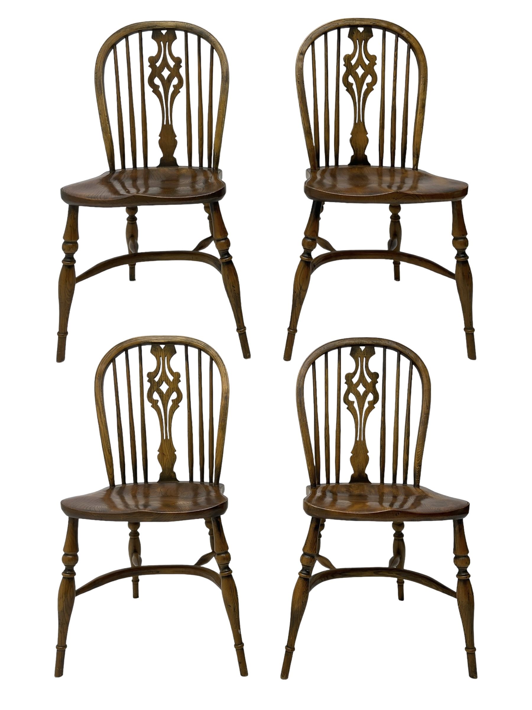 Set of four elm Windsor dining chairs, high hoop and stick back with shaped pierced splat, over shaped saddle seat, raised on ring turned supports joined by crinoline stretcher