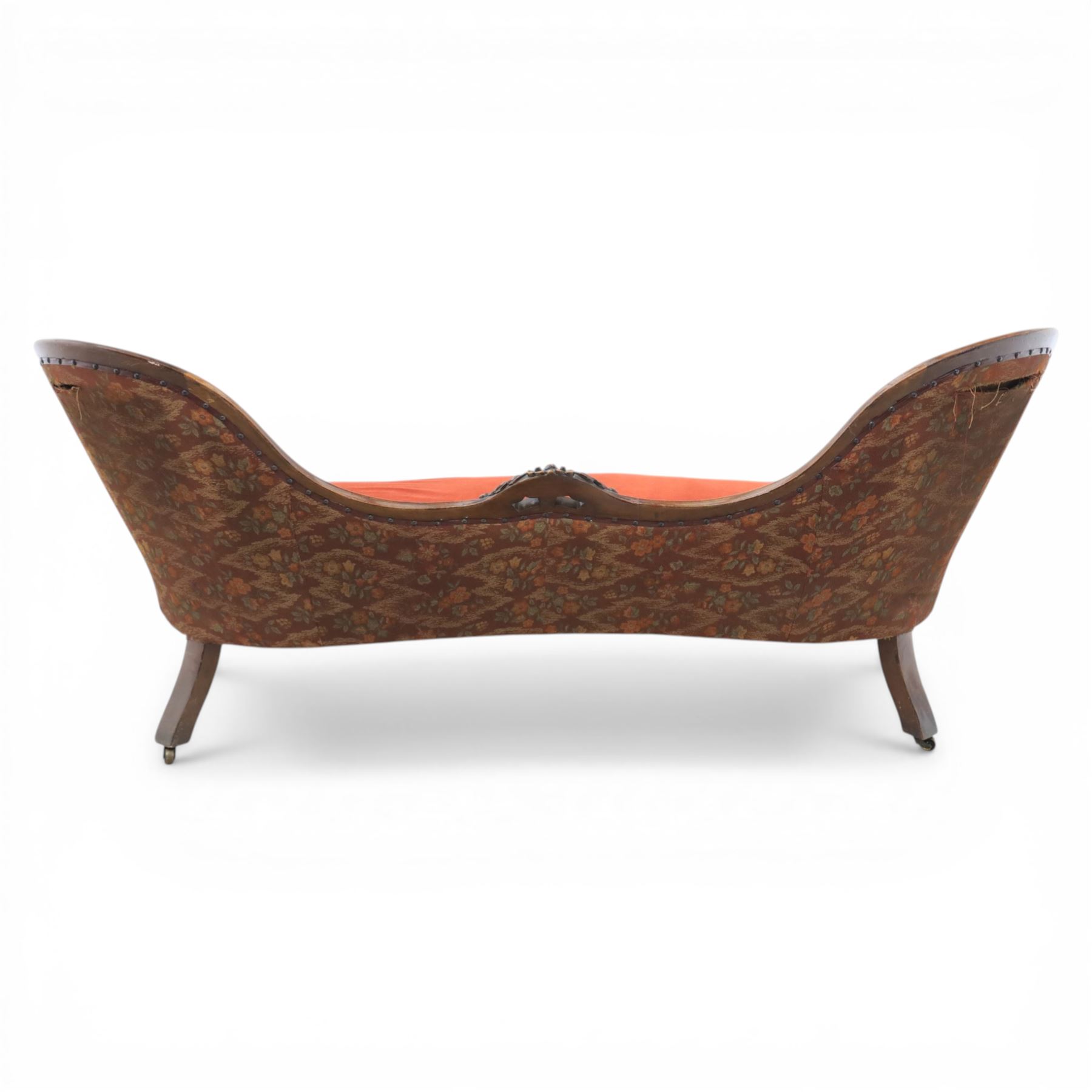Victorian mahogany framed serpentine sofa, the shaped button upholstered back with central carved foliate cartouche, and scroll arms with carved terminals, over upholstered red seat, upon carved cabriole supports with castors