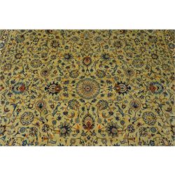 Central Persian Kashan hand-knotted carpet, pale blue field decorated with a finely drawn all-over scrolling floral vine design incorporating stylized palmettes, rosettes and foliate sprays, with a small central circular medallion, enclosed by a conforming floral vine border between multiple guard stripes, with cotton fringe ends  