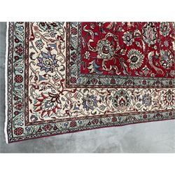 Large Persian Tabriz carpet, the red ground field decorated with multiple stylised flower heads, trailing foliage and bird and animal motifs, repeating guarded border with floral design