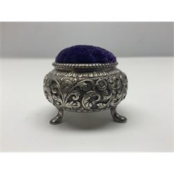 Three pin cushions, comprising gilt metal pig, silver plate shoe, circular pin cushion on threel feet, together with black pin holder with silver writing to the lid 
