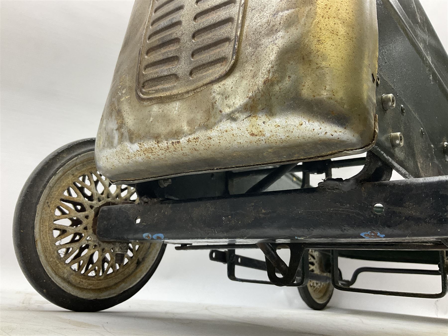 Mid 20th century pressed steel pedal car, the body painted in dark green fitted with pretend radiator to the bonnet, with spoked wheels and rubber tyres, the interior with pedals and steering wheel, L70cm