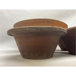 Six late 19th century terracotta bread pancheons, the bowls with glazed interiors, largest pancheon D50cm