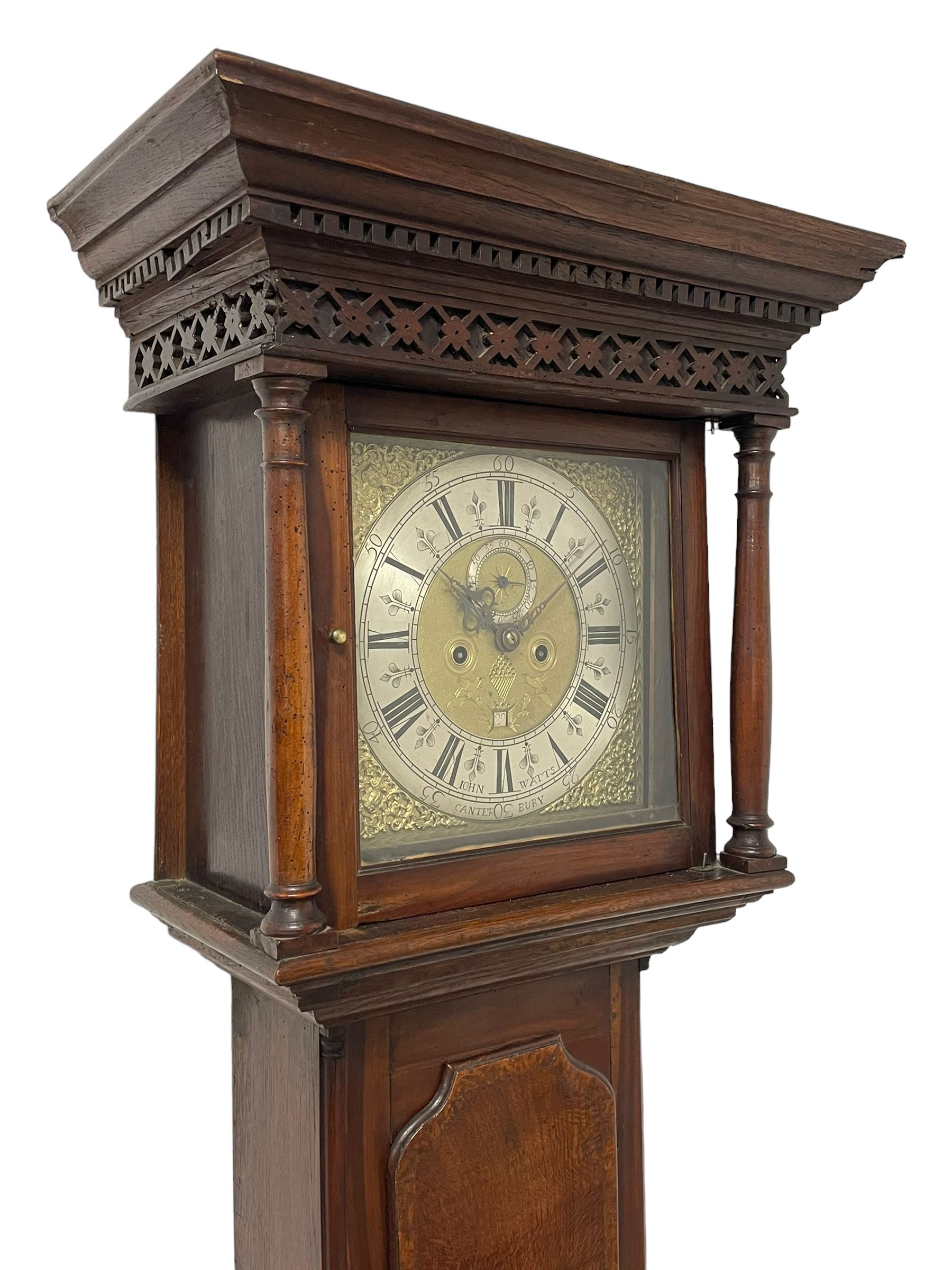 John Watts of Canterbury - early 18th century 8-day oak longcase clock, with a flat topped hood, broad cornice, dentil moulding and blind fret beneath, baluster turned pilasters with wooden capitals flanking the square hood door, trunk with recessed beaded edge and a long ogee topped door with crossbanding, plinth with applied skirting, square brass dial with matching steel hands, cast spandrels and a matted and engraved centre, date aperture, seconds ring and ring turned winding apertures, silvered chapter ring with Roman numerals, five minute Arabics, minute and quarter hour tracks, five pillar movement with a recoil anchor escapement and inside countwheel strike, sounding the hours on a bell. With weights and pendulum.