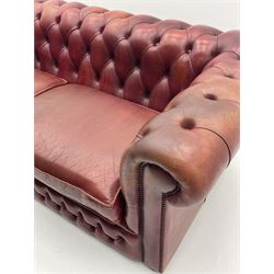 Two seat Chesterfield sofa, upholstered in a studded and deep buttoned red leather, raised on bun feet 