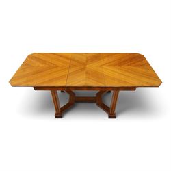 Art Deco walnut extending dining table, book-matched veneered shaped top, raised on cluster-column supports, united by stretchers, additional leaf extends to 185cm  