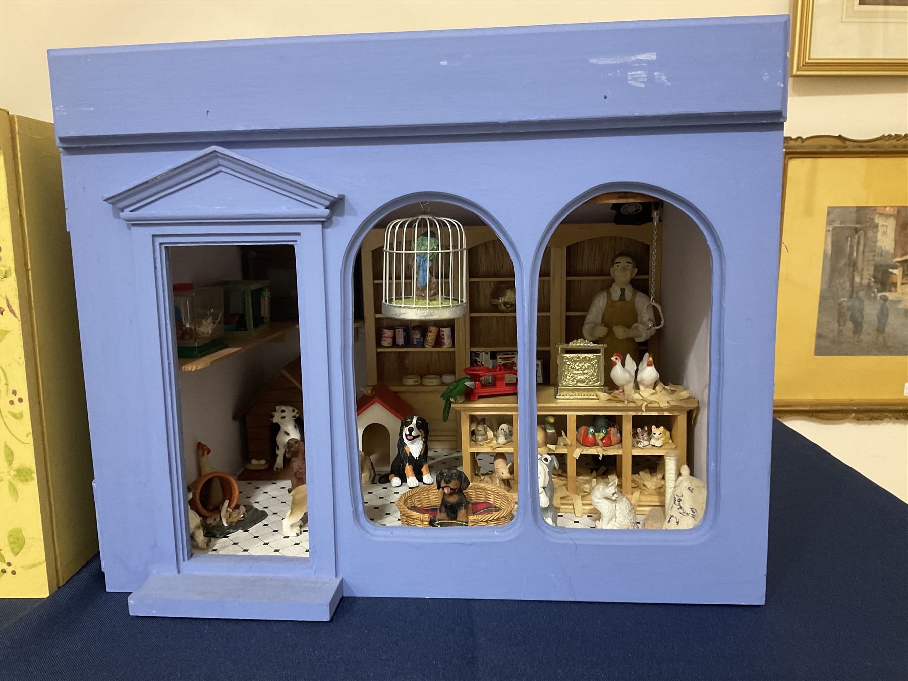 Three scratch-built wooden shop dioramas - single room Pet Shop with hinged front, fully furnished and well stocked with animals, birds and numerous accessories; and matching Garden Shop, fully furnished and well stocked with fruit, vegetables and garden accessories including lawn mower, wheelbarrows etc; each W34cm H27cm D26cm; and double fronted single room Butchers Shop with butcher at his block, partially stocked counter and two delivery cycles W57cm (3)