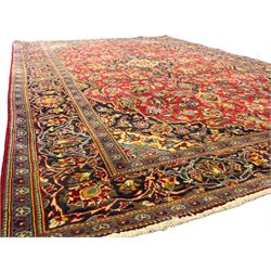 Central Persian Kashan crimson ground rug, central indigo pole medallion surrounded by sparsely placed bouquets interconnected with foliate branches, the guarded border with repeating palmette and Boteh motifs with interwoven scrolling patterns, framed by guard stripes