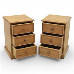 Pair of late 20th century waxed pine bedside chests, three drawers with moulded edges and turned pulls, raised on a plinth base 