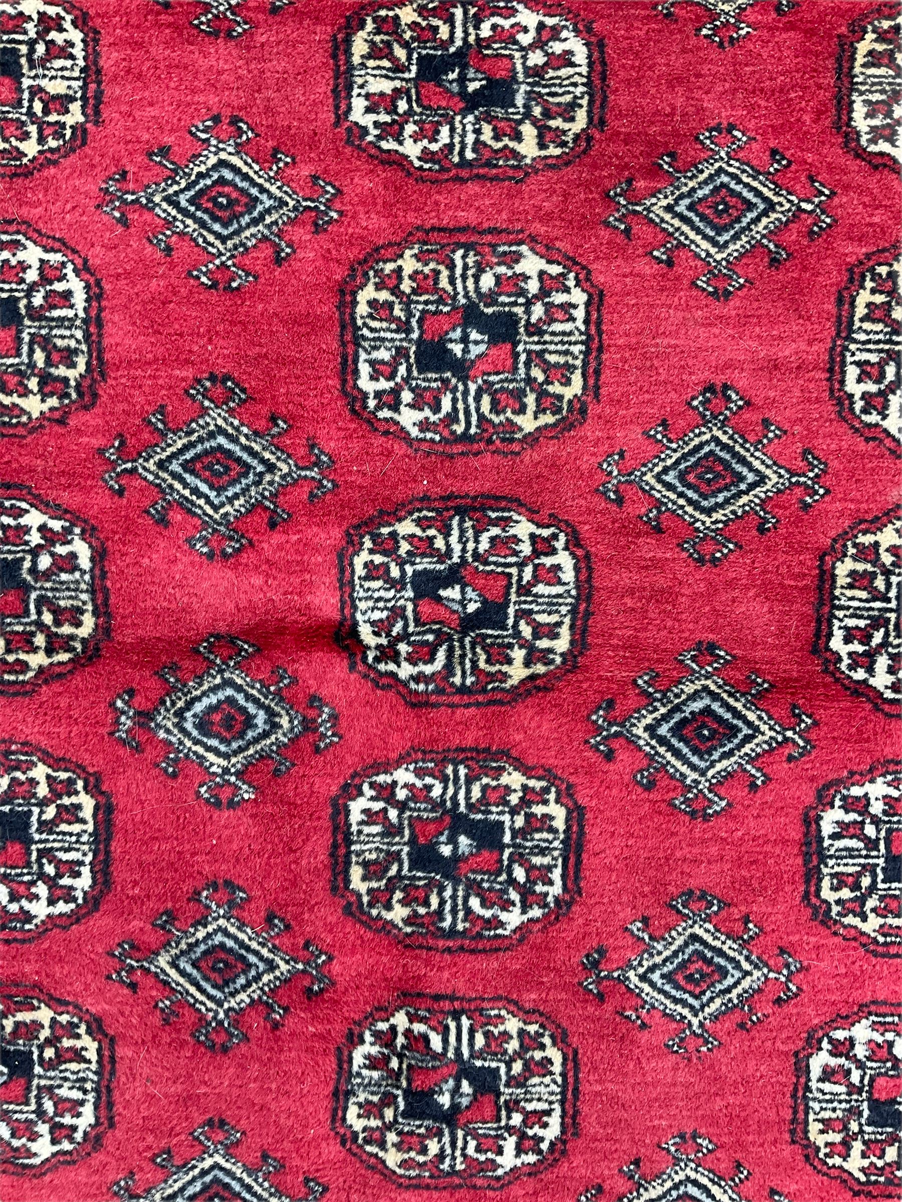 Turkmen Tekke Bokhara rug, red ground and decorated with Gul motifs, repeating multi-band border, signed on corners 