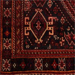 South West Persian Qashqai hand-knotted rug, madder red field with a large stepped diamond medallion with scattered geometric devices and indigo spandrels filled with geometric motifs, framed by multiple narrow guard borders and broad main border, wool fringe ends 