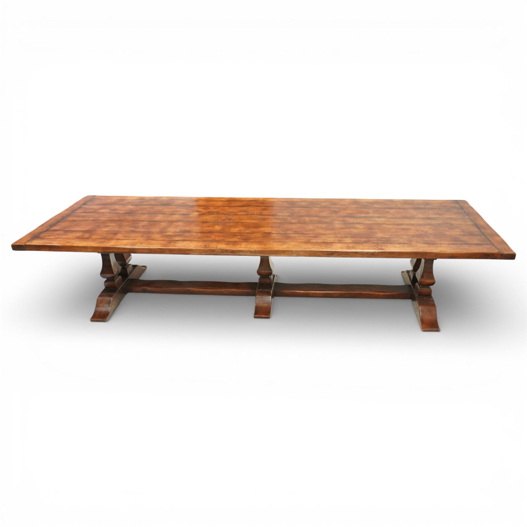 Country House 12' oak and fruitwood refectory dining table, the substantial rectangular plank top with cleated ends and chamfered edge, raised on twin trestle end square tapering and turned baluster supports with sledge feet and chamfered united by a long stretcher rail