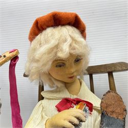 Anna Meszaros Hungary - three hand made needlework figurines - 'The Cobbler' as a child seated in a wooden rocking chair working on a removed boot H28cm; young girl in a long floral dress standing playing a harp H35cm; and young girl wearing a blue tabard standing playing a lute (3) Auctioneer's Note: Anna Meszaros came to England from her native Hungary in 1959 to marry an English businessman she met while demonstrating her art at the 1958 Brussels Exhibition. Shortly before she left for England she was awarded the title of Folk Artist Master by the Hungarian Government. Anna was a gifted painter of mainly portraits and sculptress before starting to make her figurines which are completely hand made and unique, each with a character and expression of its own. The hands, feet and face are sculptured by layering the material and pulling the features into place with needle and thread. She died in Hull in 1998.  