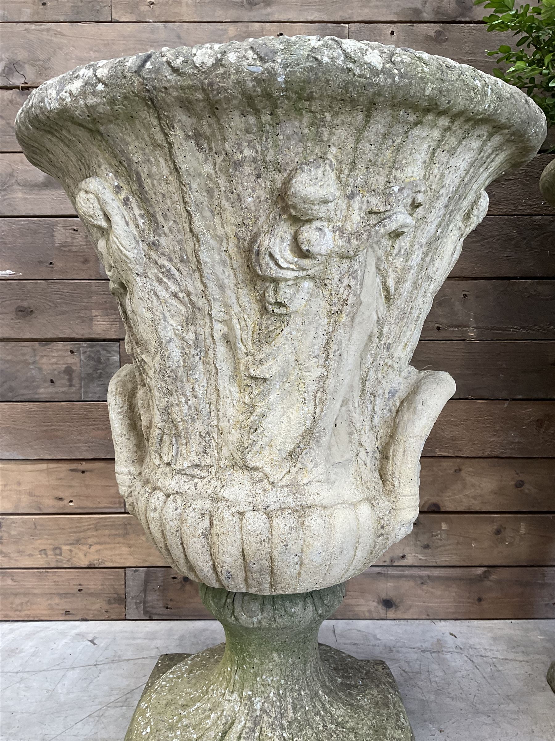 Set of four Victorian design cast stone Grecian urns, tapering form cast with figures and handles, square plinth bases