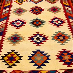 South West Persian Qashqai flatweave kilim, ivory field decorated with rows of multicoloured stepped diamond medallions composed of angular geometric motifs, enclosed by bold polychrome borders of triangular devices and stylized geometric, ornamentation, with fringe ends 