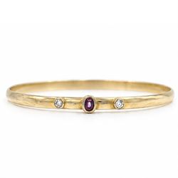 18ct gold ruby and diamond bangle, single oval cut ruby set between two round brilliant cu...