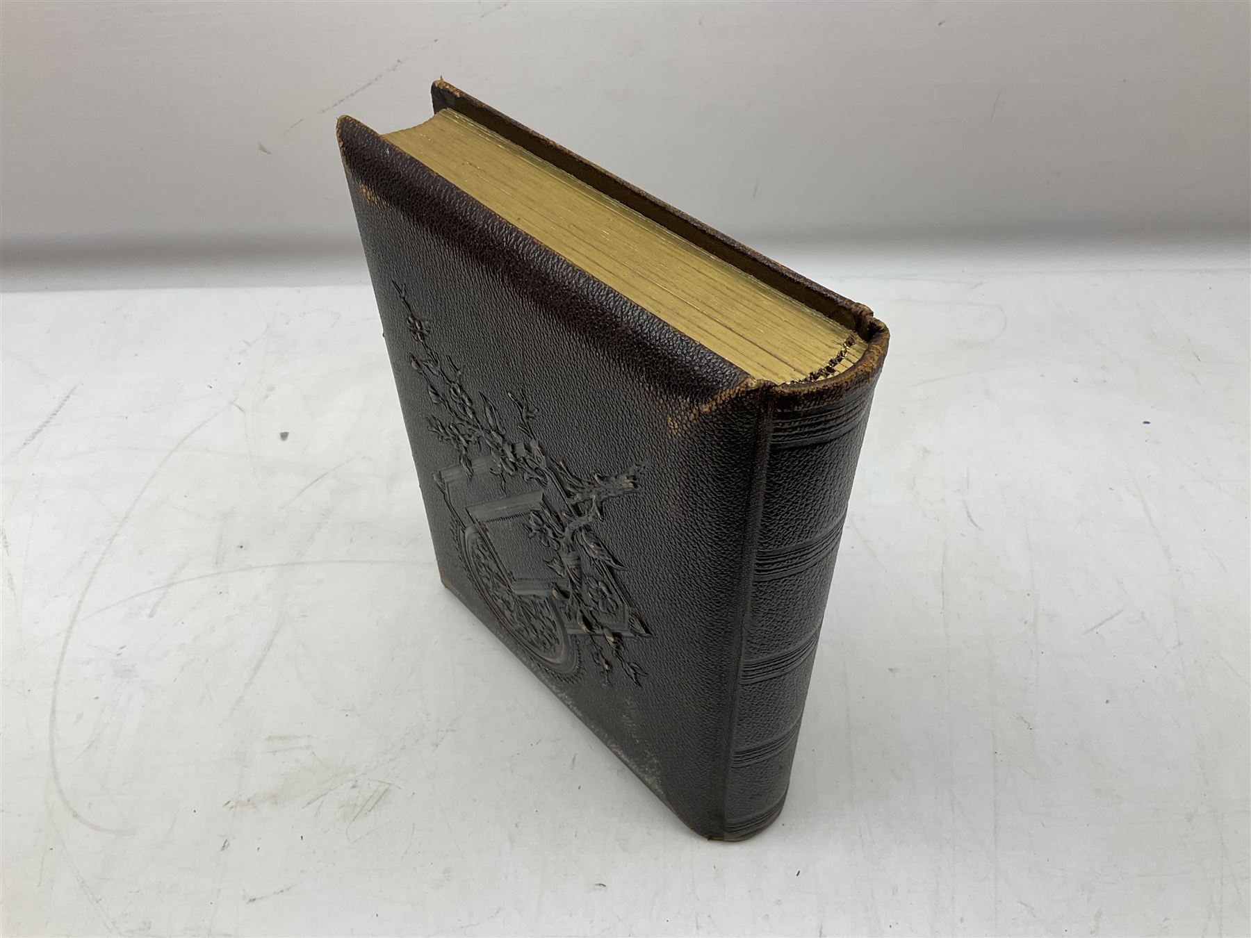 Victorian leather bound photo album, the interior leaves containing apertures of various sizes and shapes of portraits surrounded by printed floral designs, H28cm