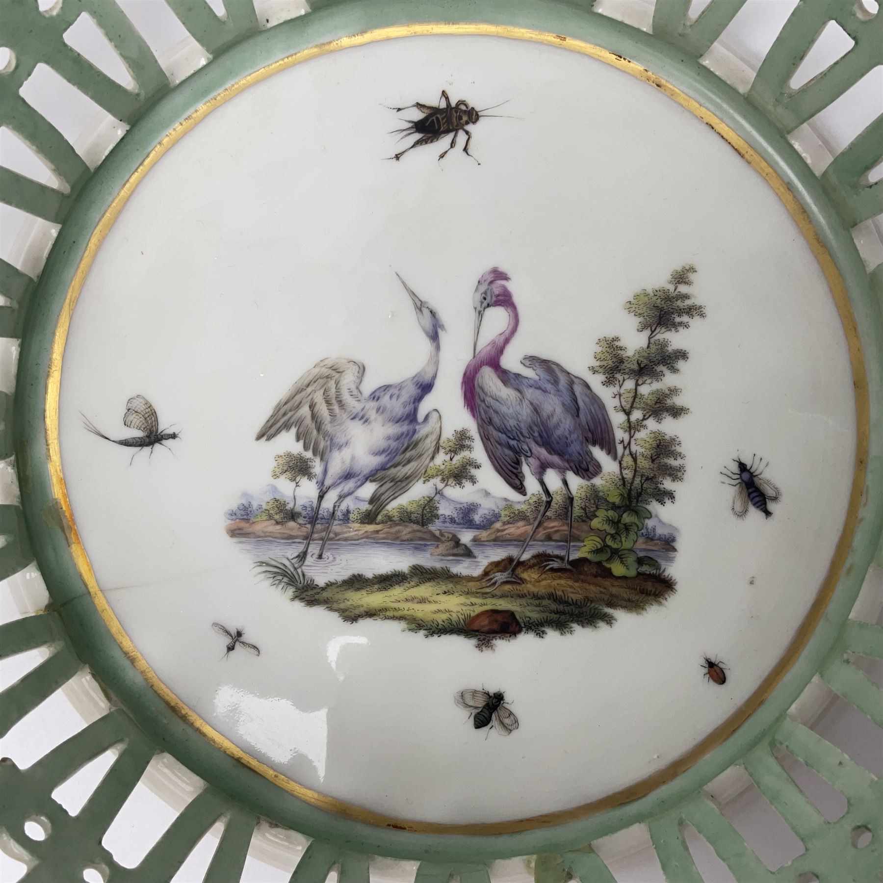 Pair of 19th century German openwork chestnut baskets, with twin handles and scrolling gilt border and star rim, painted to the centre with birds and insects, D22cm 