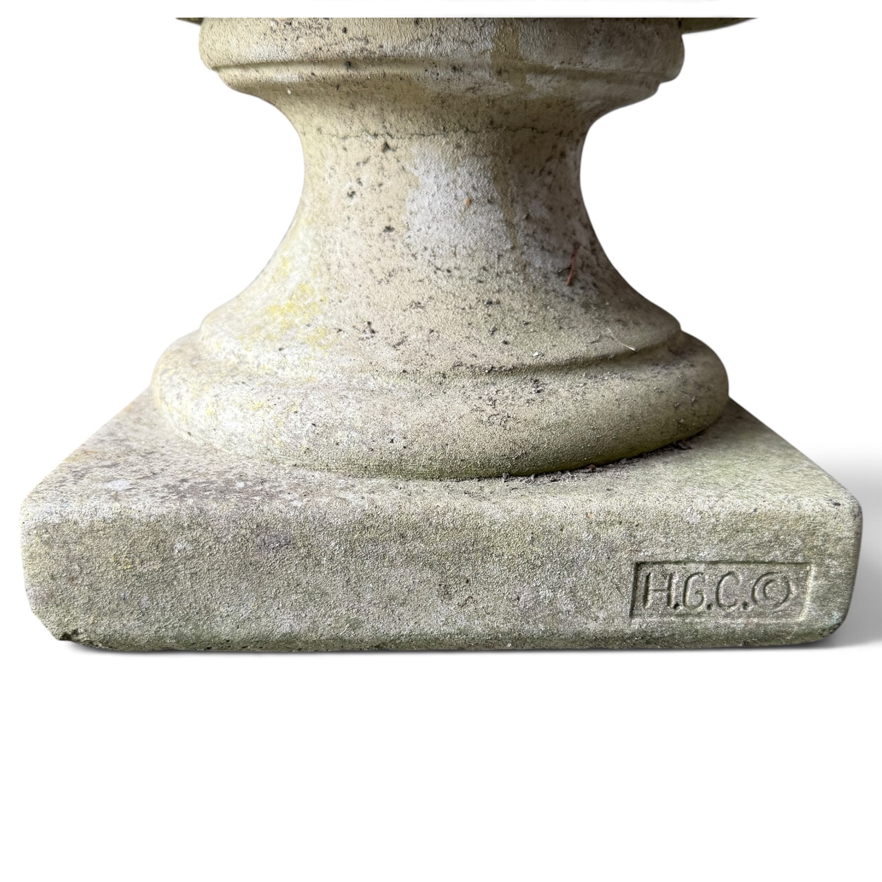 Regency design weathered cast stone garden urn of kylix form, the anthemion and arrowhead moulded everted rim over a fruiting laurel and lion-mask relief decorated body, waisted socle on square base, stamped HGC