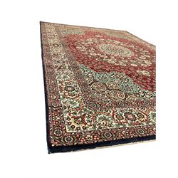 Persian design crimson ground carpet, the central rosette medallion surrounded by scrolling leaves and flower heads, the spandrels decorated with floral design and scrolling foliage, repeating border within guard stripes