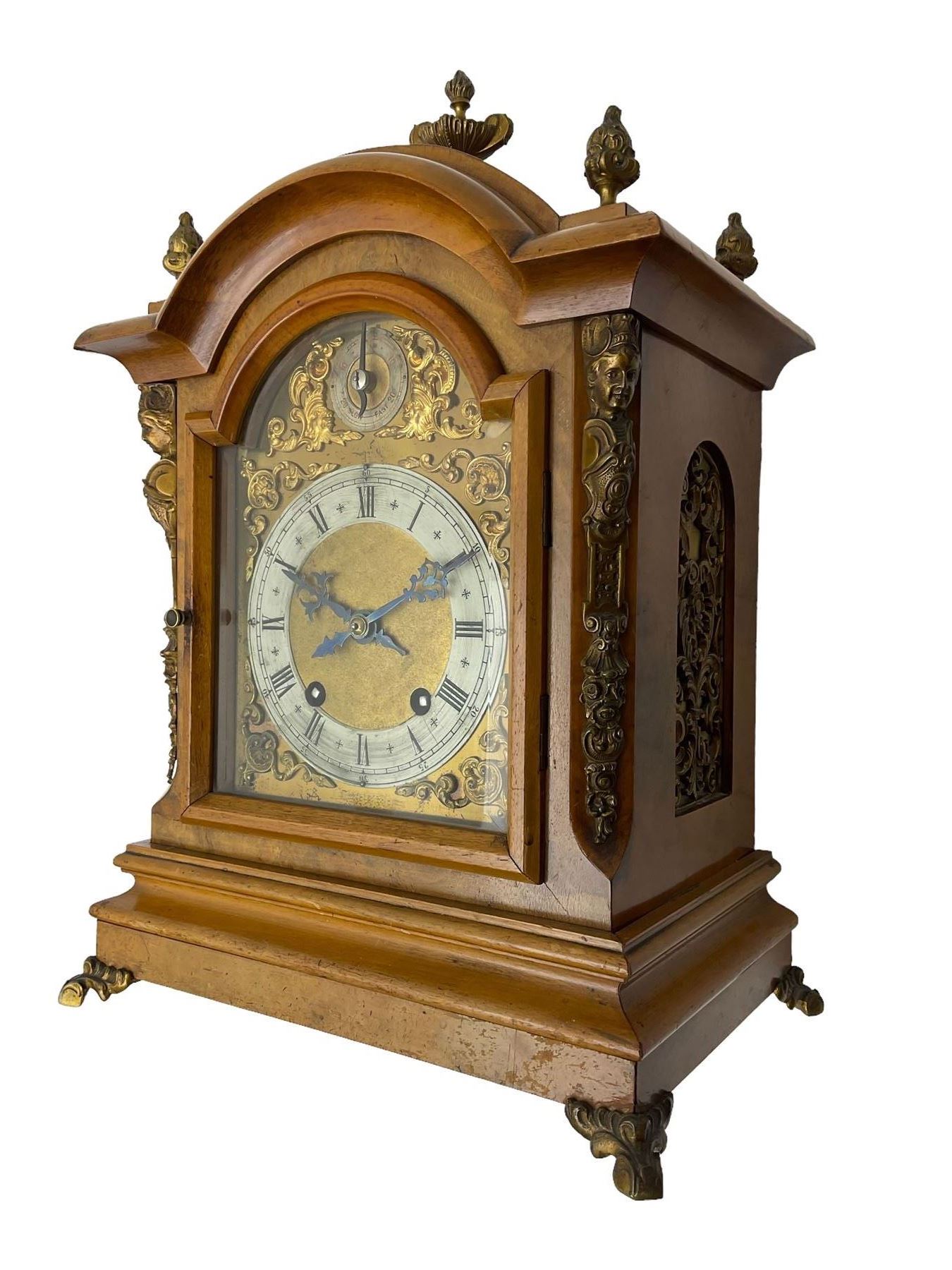 German - 19th century 8-day walnut bracket clock, striking the quarters on two coiled gongs, case with a break-arch top surmounted by cast brass finials, canted corners to the front with cast brass caryatids and sound frets to the sides, brass break arch dial with a silvered chapter ring, steel gothic hands, spandrels, and pendulum regulation dial. With pendulum.
