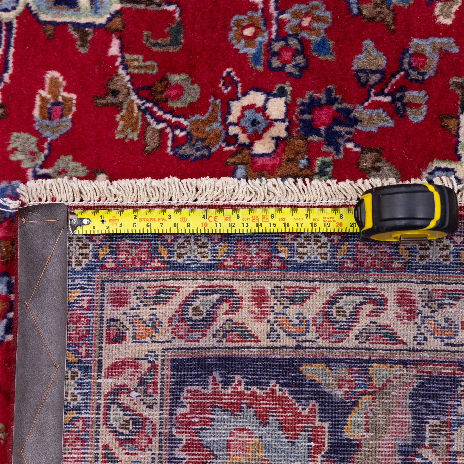 North East Persian Mesued hand-knotted carpet, deep red field with a finely drawn central elongated medallion of navy and ivory, issuing delicate scrolling vines, palmettes and floral sprays in a dense all-over composition, main border on dark ground decorated with a continuous palmette and vine scroll, flanked by multiple narrow guard stripes incorporating rosettes and stylized floral devices, with cotton fringe ends 