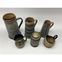 Five Victorian Doulton Lambeth Silicon Ware jugs, and a tankard, the largest example with relief moulded foliate decoration in tones of brown and blue, H24cm. 