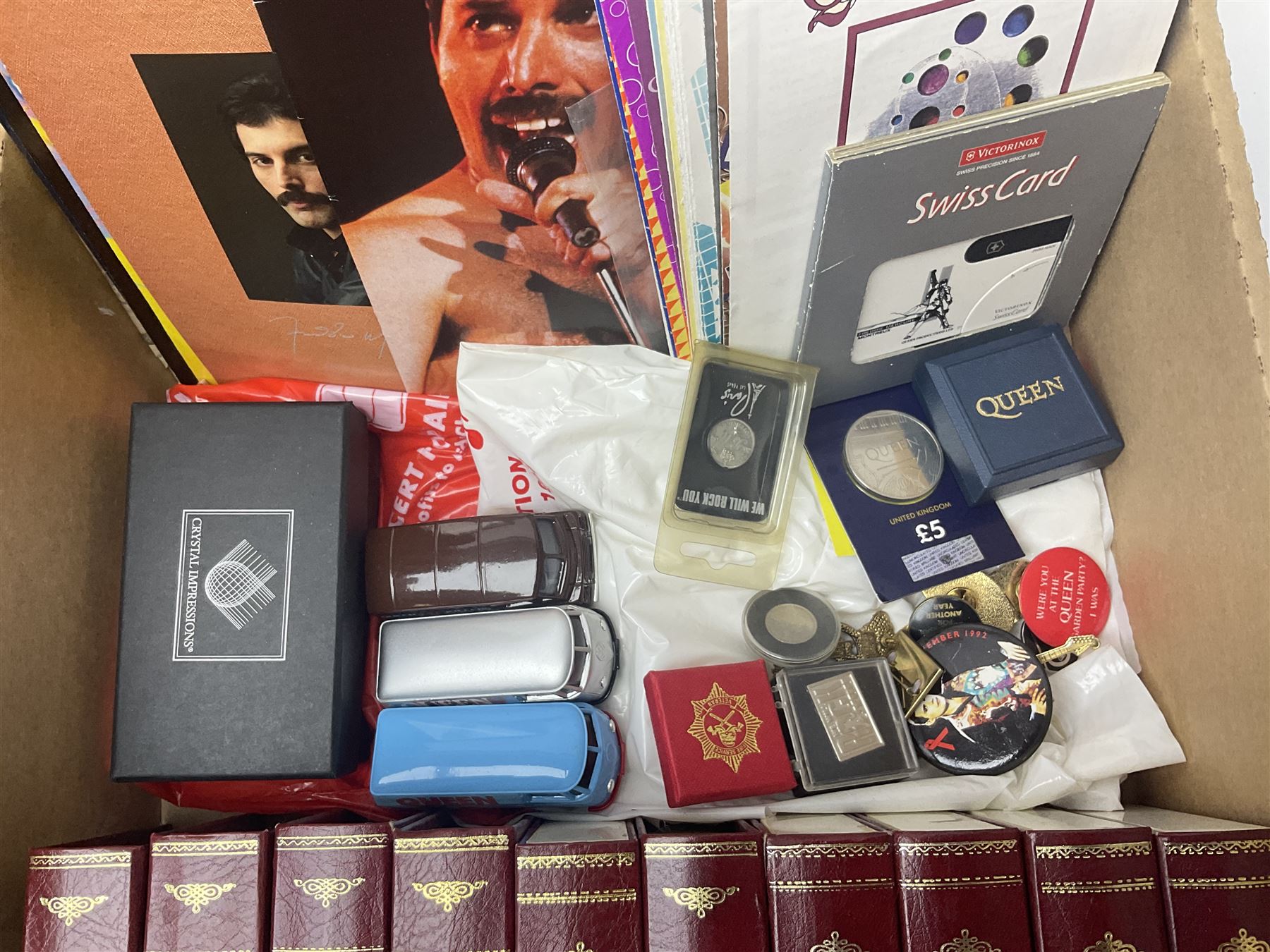 Mostly Queen and Freddie Mercury interest items, including pin badges, newspaper cuttings, diecast 'promotional' vehicles, special edition Pop Rocks figure of Freddie Mercury, VHS tapes, two charity certificates signed by Brian May and Roger Taylor, poster etc, in two boxes 