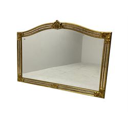 Gilt cushion framed wall mirror, arched top with central stylised fleur-de-lis decoration and cartouche corners