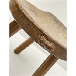 'Mouseman' oak three legged stool with dished kidney shaped seat, tapered octagonal supports, with carved mouse signature, by Robert Thompson of Kilburn 