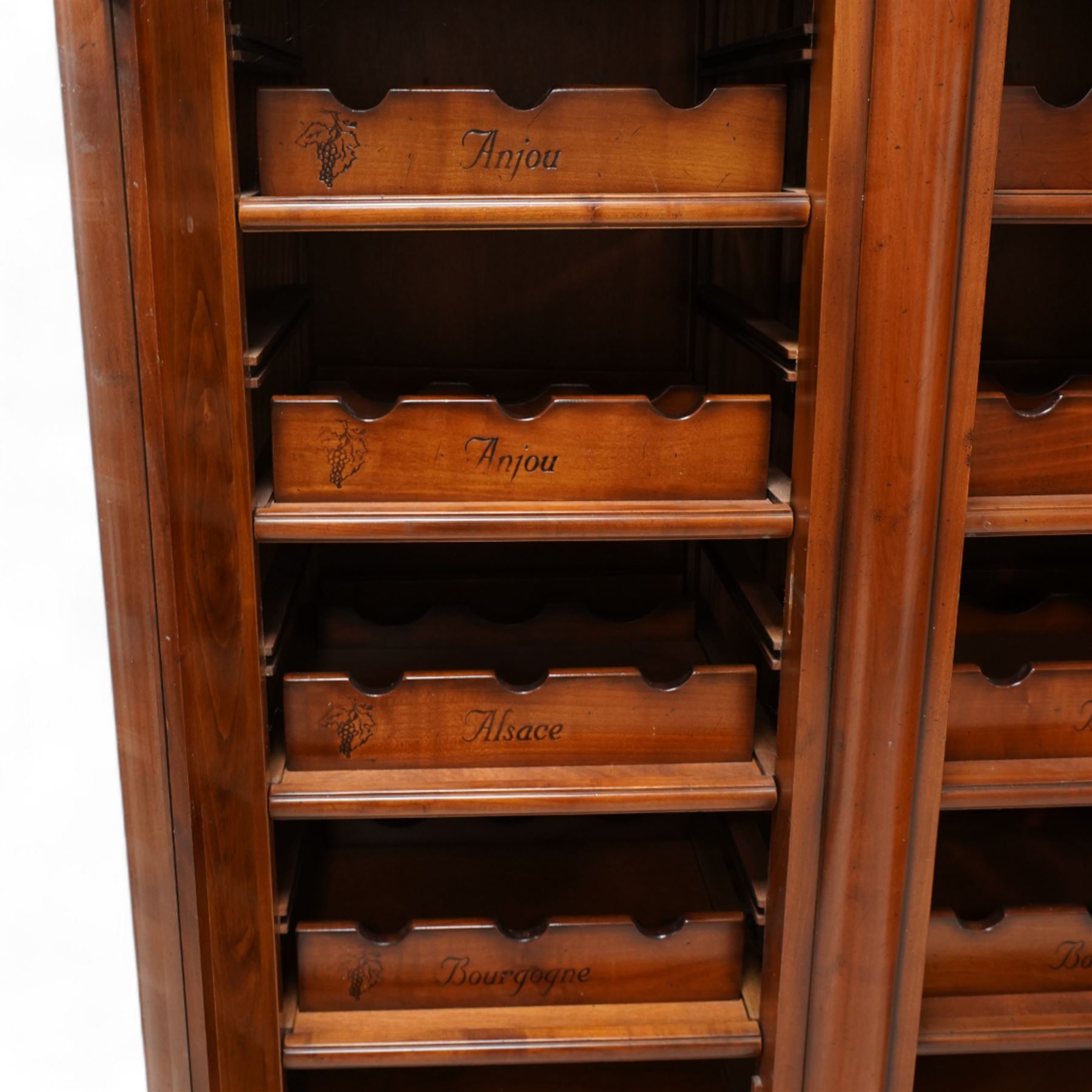 Cherrywood wine rack cabinet, moulded rectangular top over two glazed doors, fitted with eight slides each with three bottle holders inscribed with various wine types, single long drawer to the base 