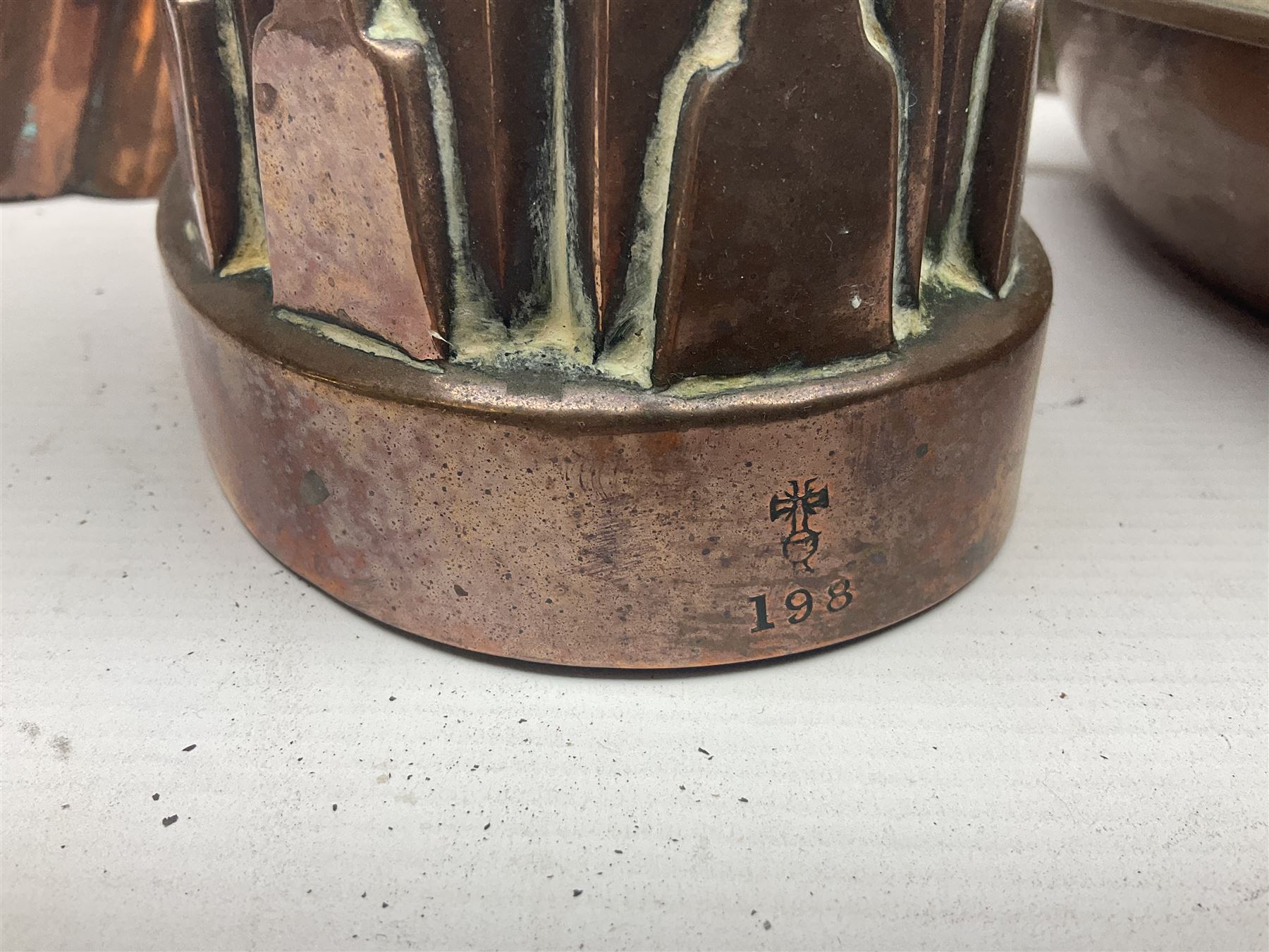 Four Victorian copper moulds, together with a graduating set of copper pans with wooden handles and finials to covers, largest pan 