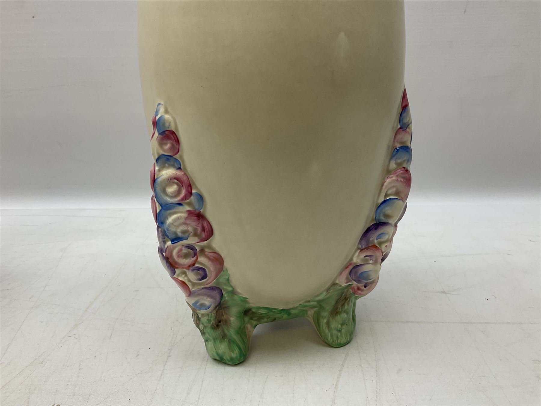 1930s Carlton Ware Art Deco Garden pattern vase of shouldered ovoid form, decorated with blue, pink and yellow flower heads on a mottled blue and white ground, pattern no. 3413, with printed and painted marks beneath, H19cm, together with a Clarice Cliff My Garden pattern vase, raised upon three feet with blue, pink and purple moulded Hollyhock design, H20cm, with Clarice Cliff Wilkinson Ltd England marks beneath