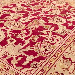 Large Persian Savonnerie-inspired style flatweave kilim, crimson field with central stylized palmette medallion with bold scrolling vinery and angular floral motifs between multiple guard stripes, rendered in tones of soft cream, pale sage, and muted terracotta, with fringe ends 