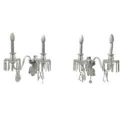 Pair of cut glass two branch wall sconce candelabras, each with S scroll extending branches with shaped and bevelled circular drip trays, hung with pendant drops