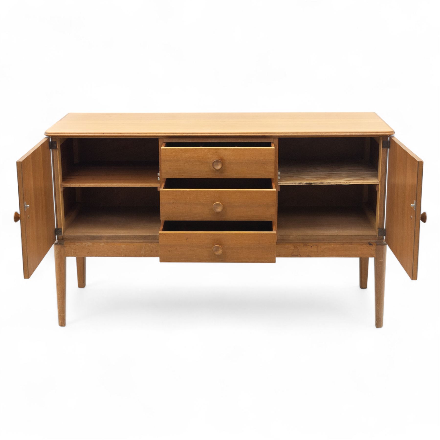 Gordon Russell - mid century modern teak sideboard, the rectangular top with rounded edges over twin cupboards and three central drawers, fitted with circular wooden pulls, on tapered supports, reflecting the firm’s commitment to simplicity and quality materials during the post-war design period