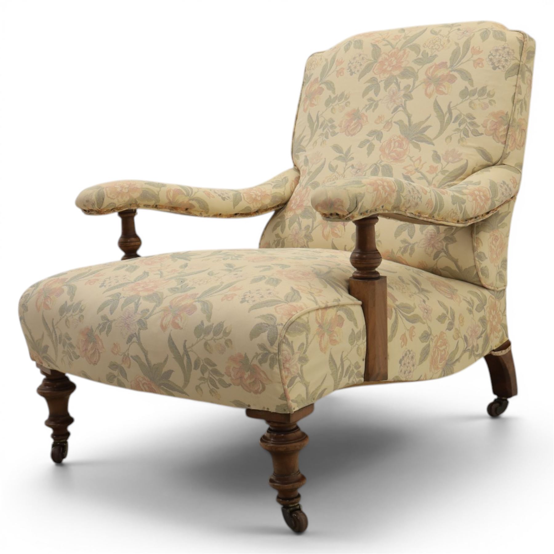 Victorian mahogany framed deep seat low drawing room chair, upholstered in beige floral fabric, on turned supports terminating in castors