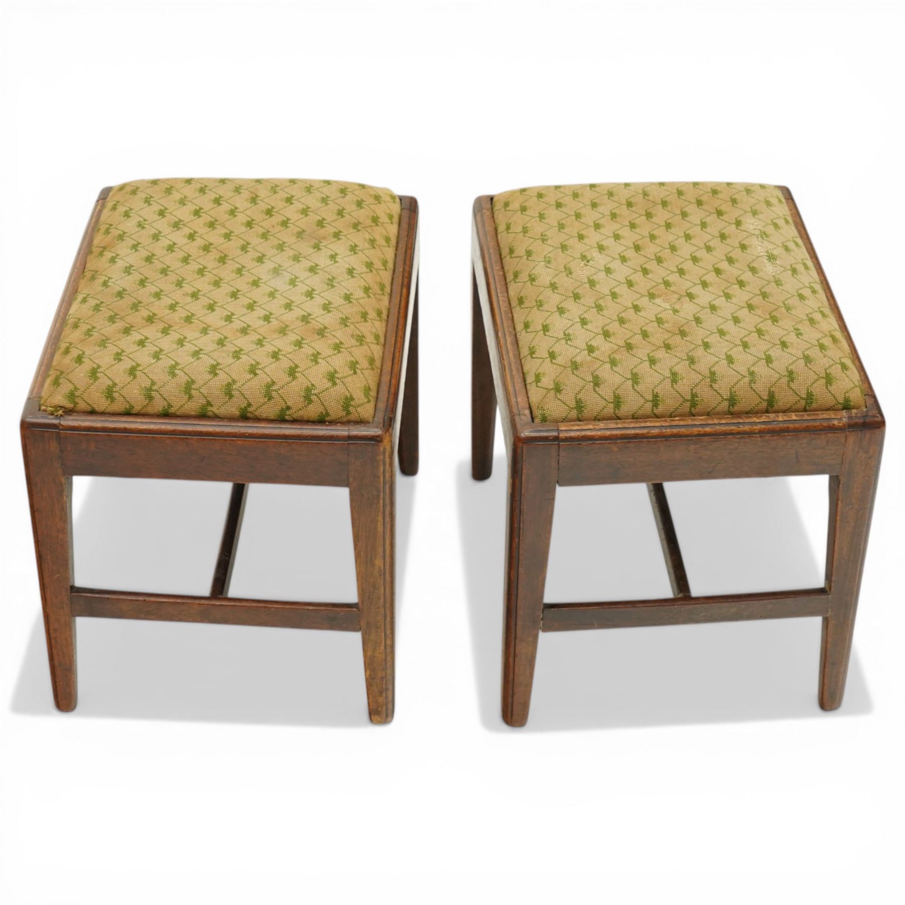Pair of George III mahogany framed coaching stools, the drop-in seats upholstered in green and beige needlepoint fabric, raised on moulded and chamfered square tapering supports united by H-stretcher