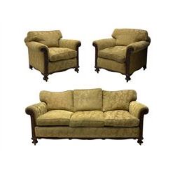 Early 20th century mahogany framed three-piece lounge suite - three-seat camelback sofa (W203cm, D105cm); pair of matching armchairs (W95cm, D96cm); upholstered in neutral foliate pattern fabric, carved with trailing leafy branches, ball and claw carved feet with brass castors 