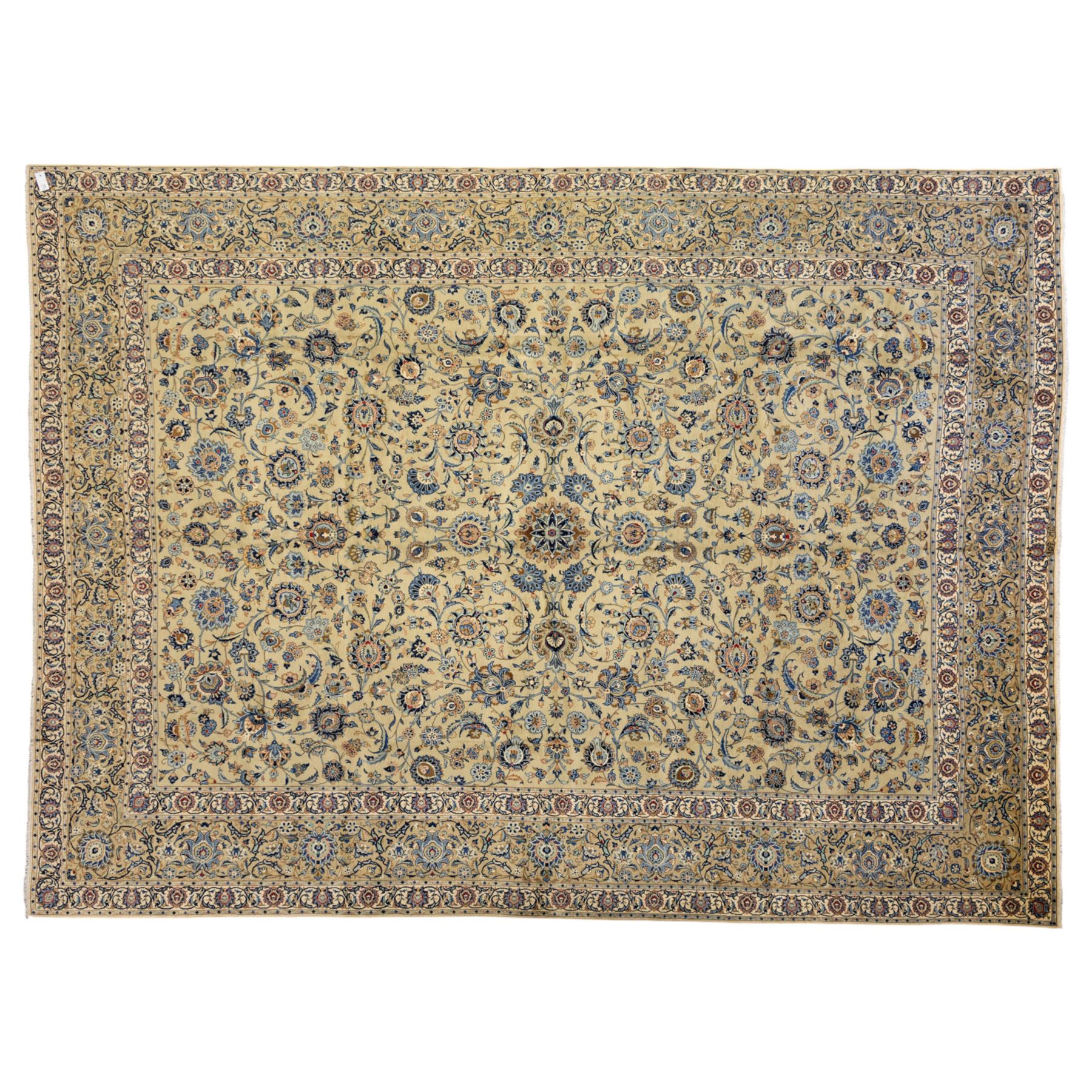 Persian Kashan carpet, beige ground, field with an all-over design of scrolling palmettes and floral sprays in blue and terracotta within a ivory ground and pale blue floral border